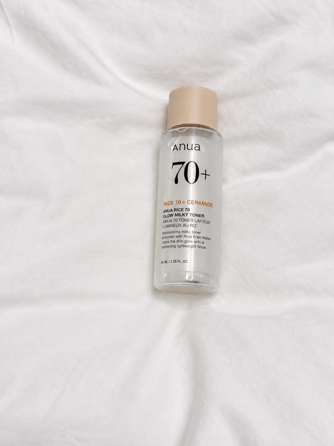Anua Rice 70 Glow Milky Toner on white fabric